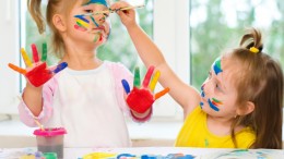 two little girls painting with paintbrush and colorful paints