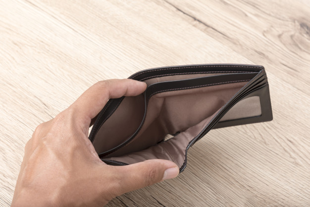 Close up of hand opens an empty wallet on wooden background.